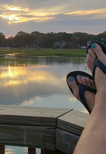Sunset on the Crabdock Relaxed view of the water from a crab dock with crossed feet, painted toes, and sandals at sunset