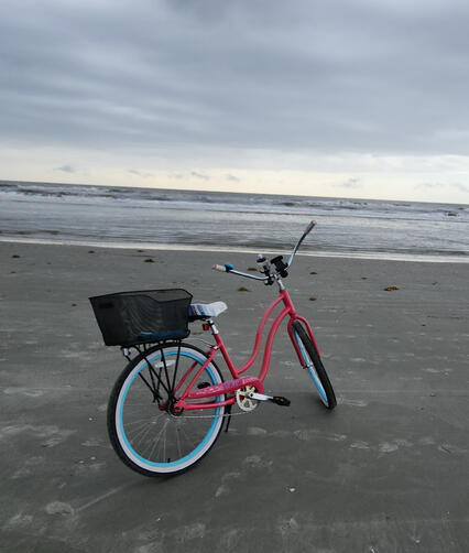 Red beach cruiser bike parked on the hard-packed sand at low tide.
